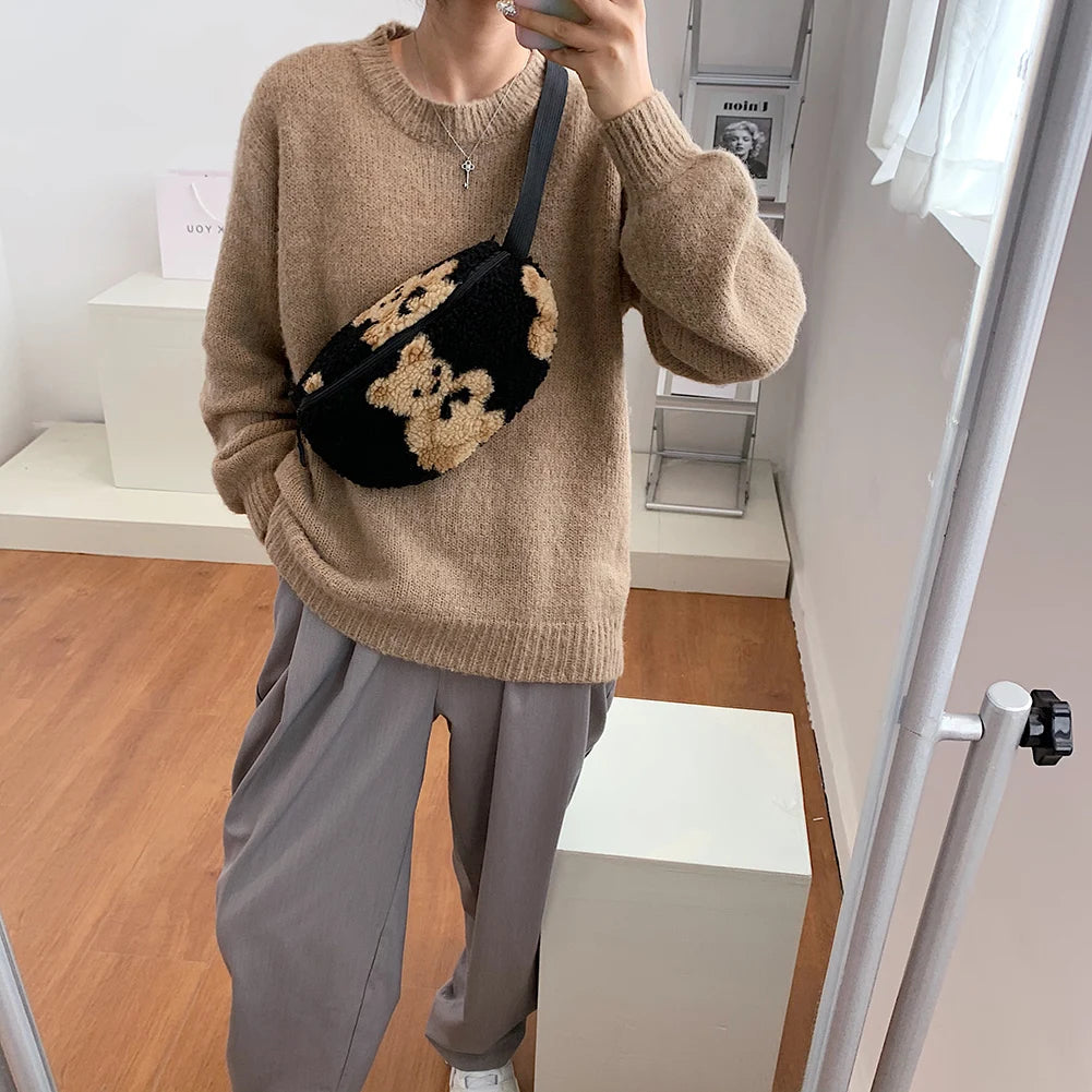 Sac banane moumoute noir à fleurs beiges porté en bandoulière sur un pull oversize beige — sac banane doux et tendance pour femme